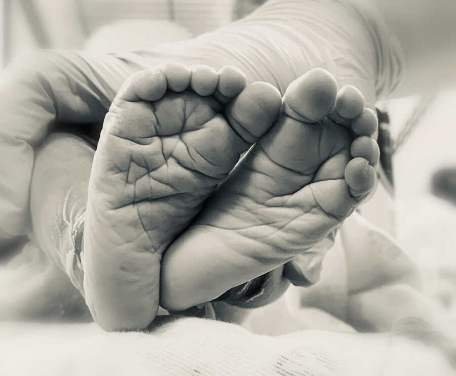 close up of the bottoms of the newborn baby feet being held up by a hand