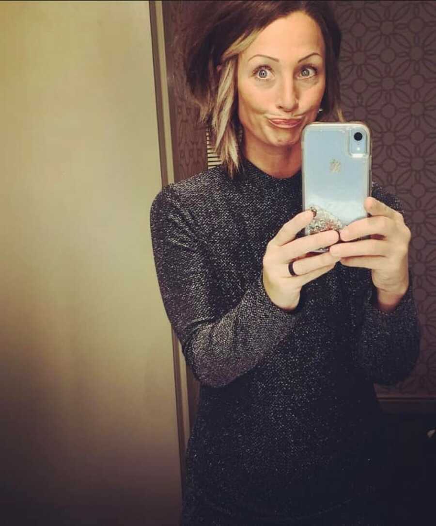woman making a face while taking a selfie in the mirror