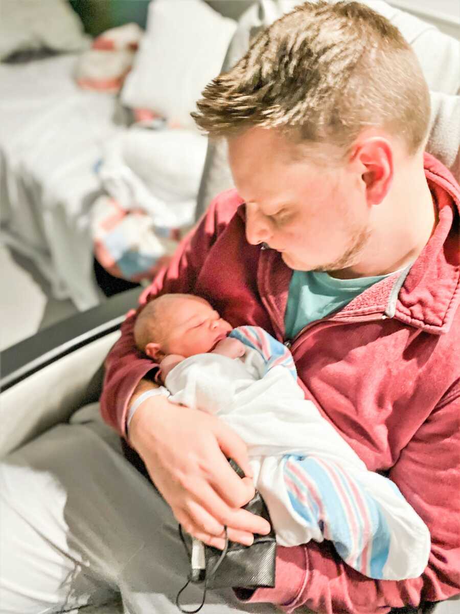 Dad holding newborn baby in his arms while staring at her 