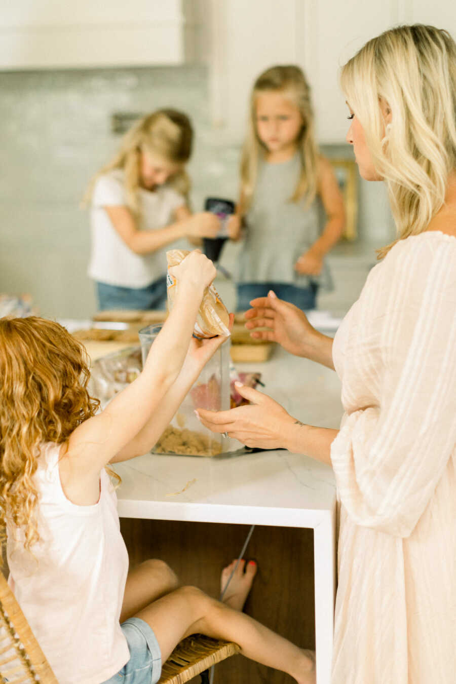 Little girl passes loaf of bread to her mom as they make sandwiches together