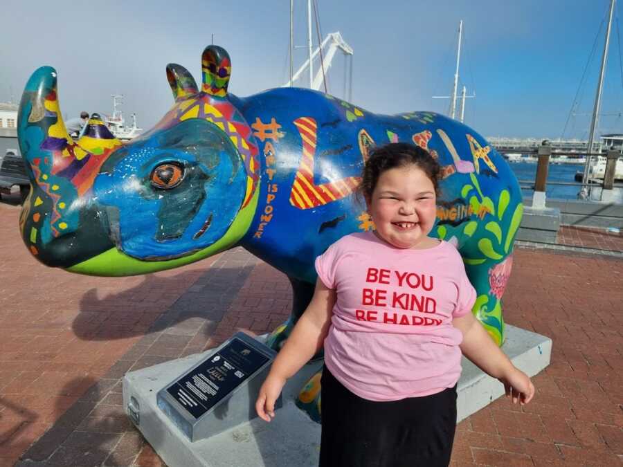 little girl posing in front of an animal