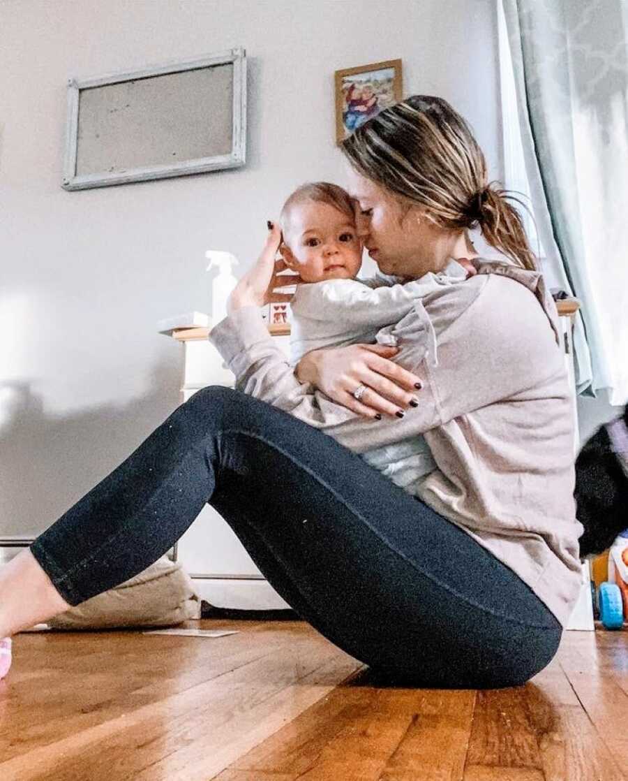 Mom sits on the floor and snuggles her youngest child