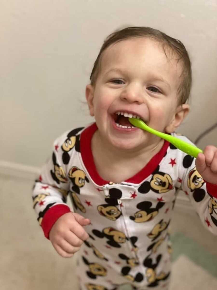 son learning to brush his teeth and smiling