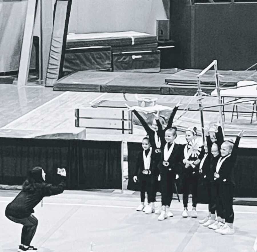 Mom snaps a photo of her daughter competing in a gymnastics competition