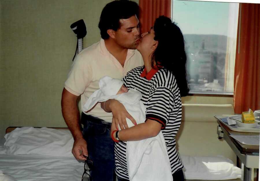 mom and dad with their first child kissing