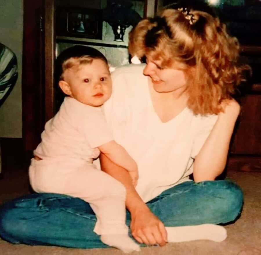 Young mom sits on the floor and holds her toddler daughter