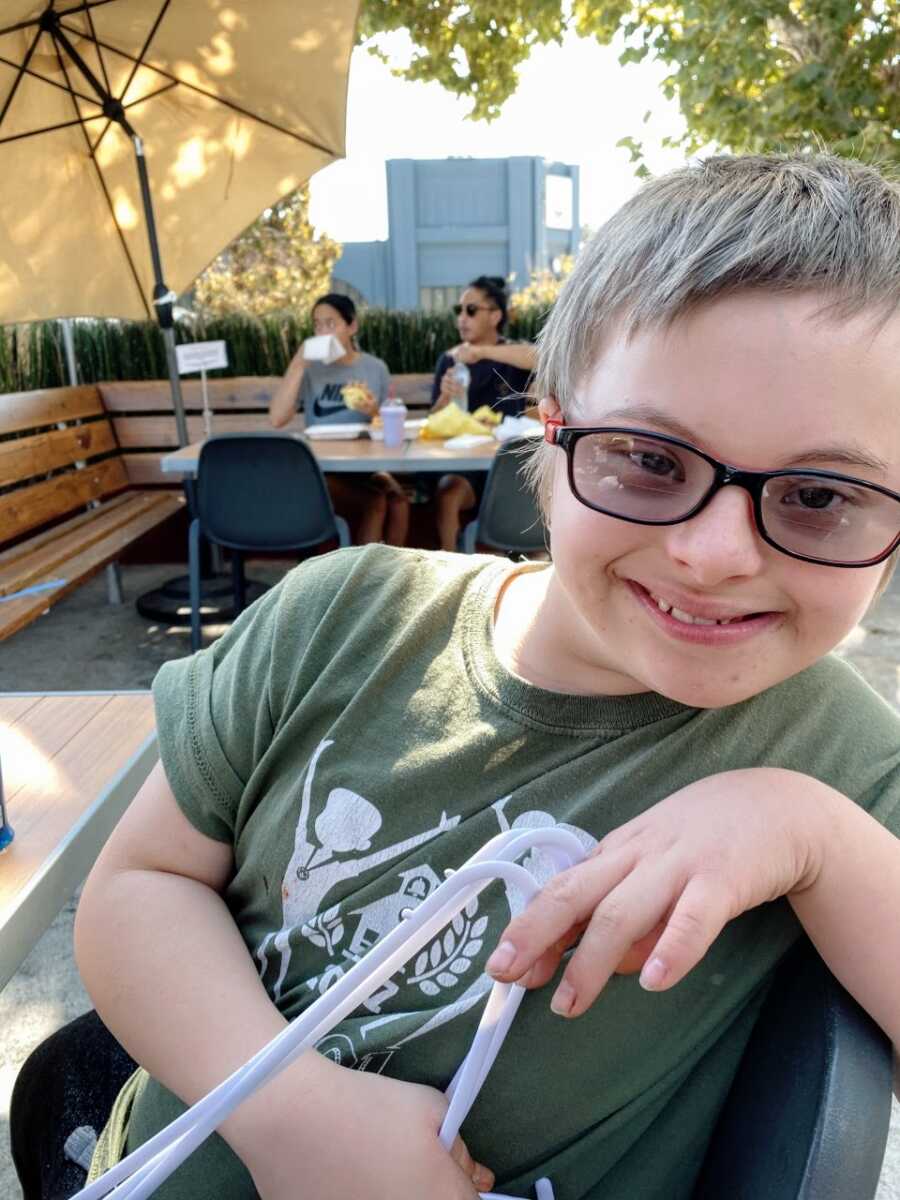 Mom takes photo of son with Down syndrome while enjoying a meal at a restaurant together