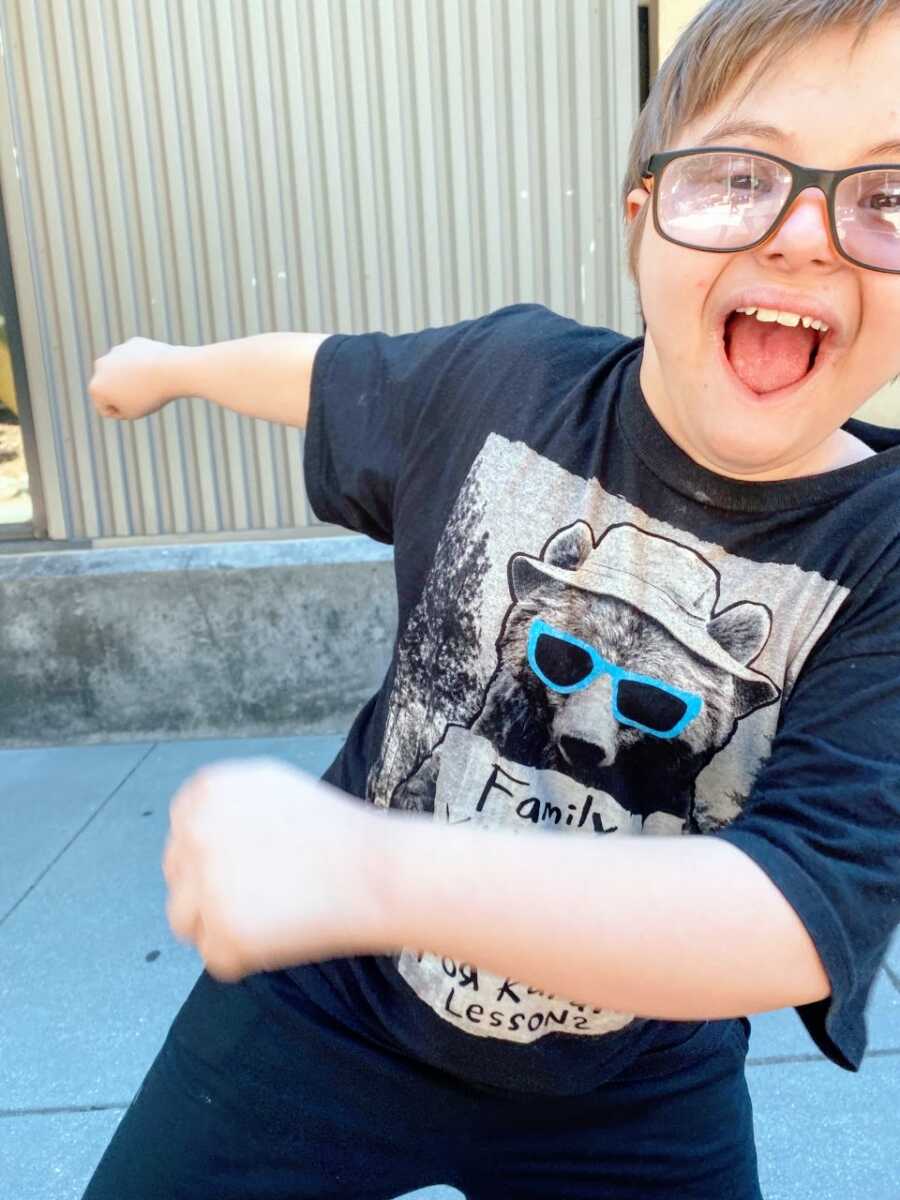 Little boy with Down syndrome dances around and sticks his tongue out