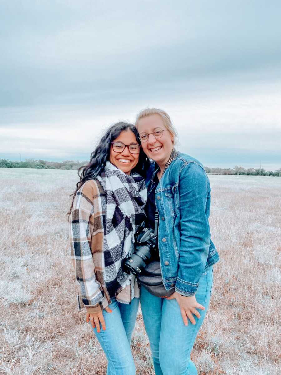 Young woman takes a photo with her adoptive mother in a field