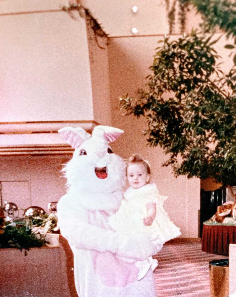 A person dressed as the Easter bunny holds a young girl
