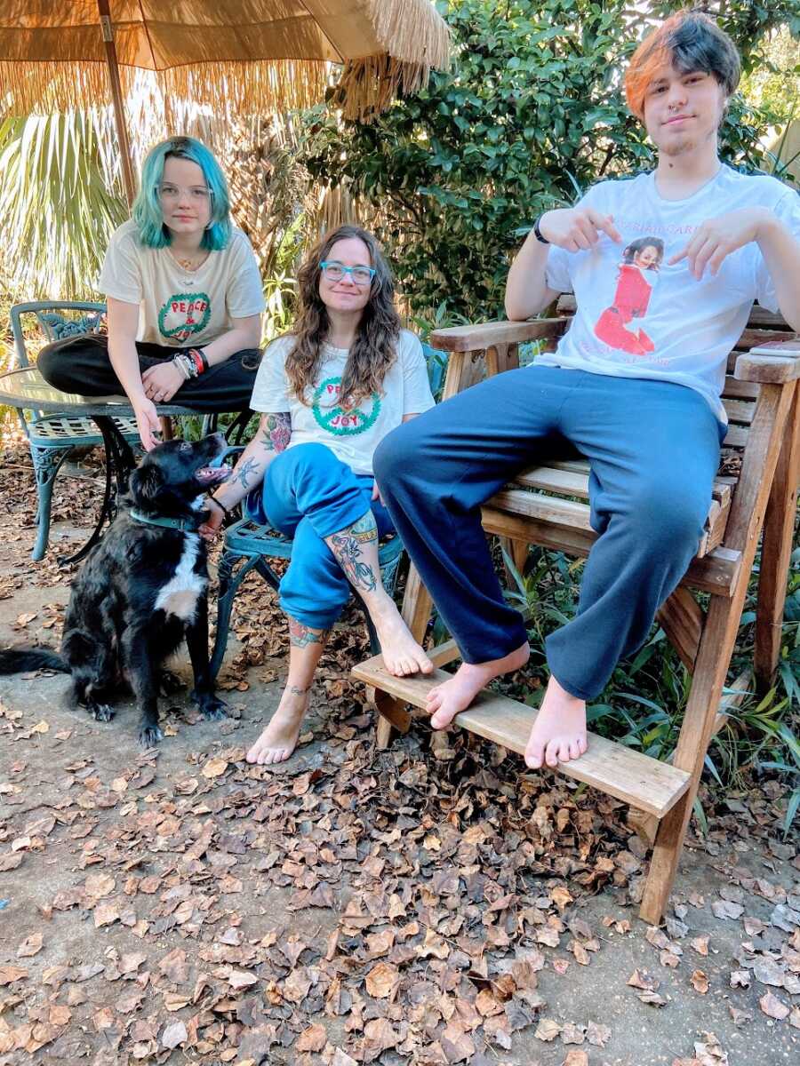 A mom sits with her two children outside in the fall