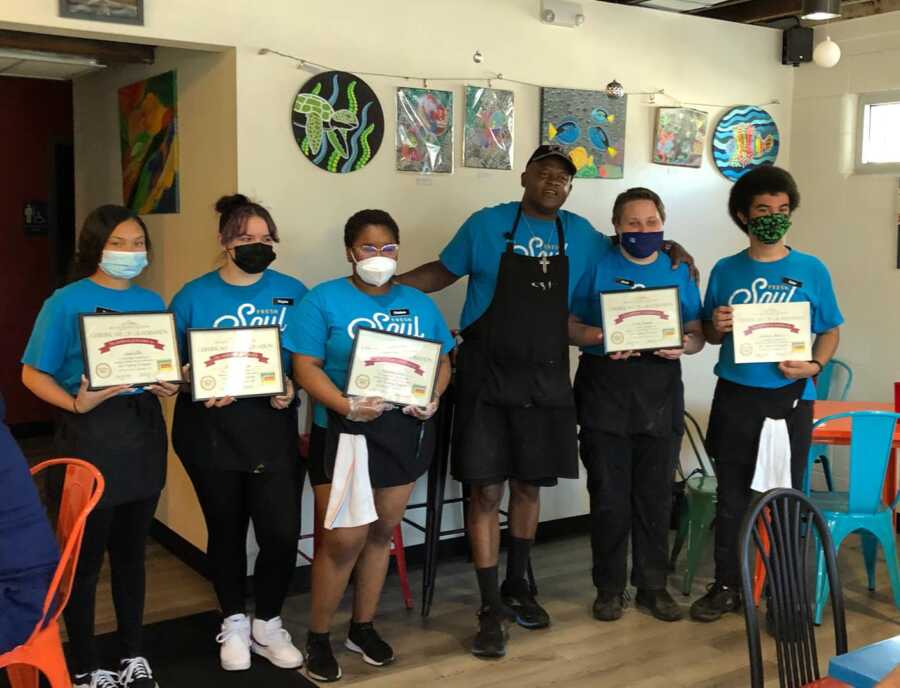 Michael Brown takes a picture with the youth he's mentored in his restaurant. 