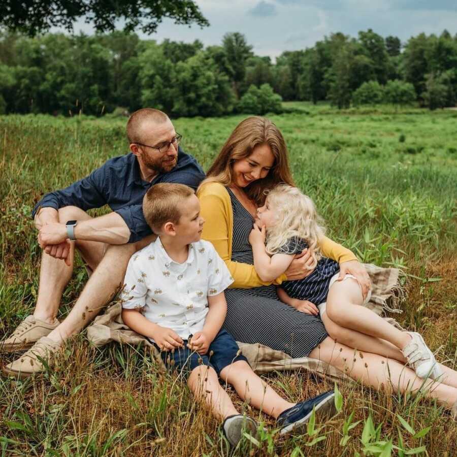 Family pictures with husband, wife, little girl, and little boy sitting in the grass.