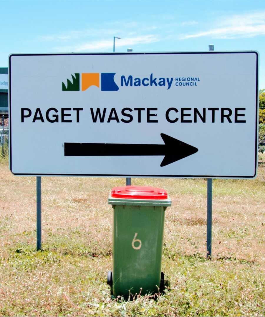 garbage bin placed in front of a sign for a waste centre