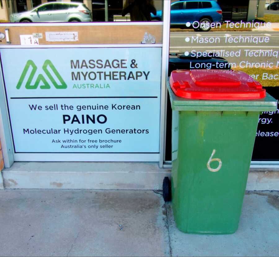 garbage can placed next to the door of a massage and myotherapy building