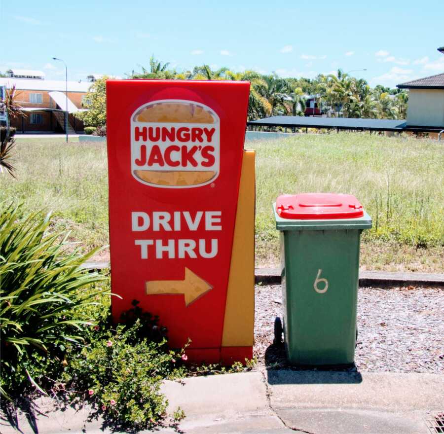 individual takes out neighbor's garbage can and takes it to a Hungry Jacks drive thru