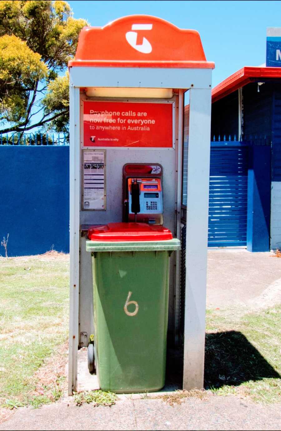 a garbage can is placed in a phone booth on a street