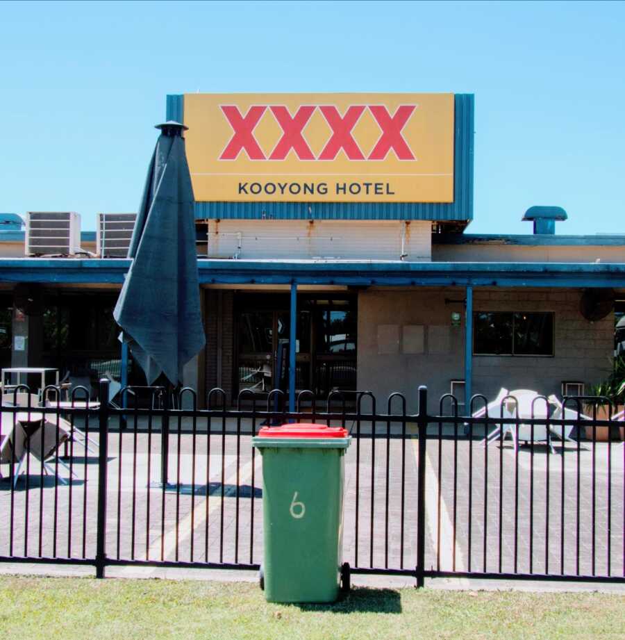 person brings their neighbor's garbage can out by taking it to a hotel in the area