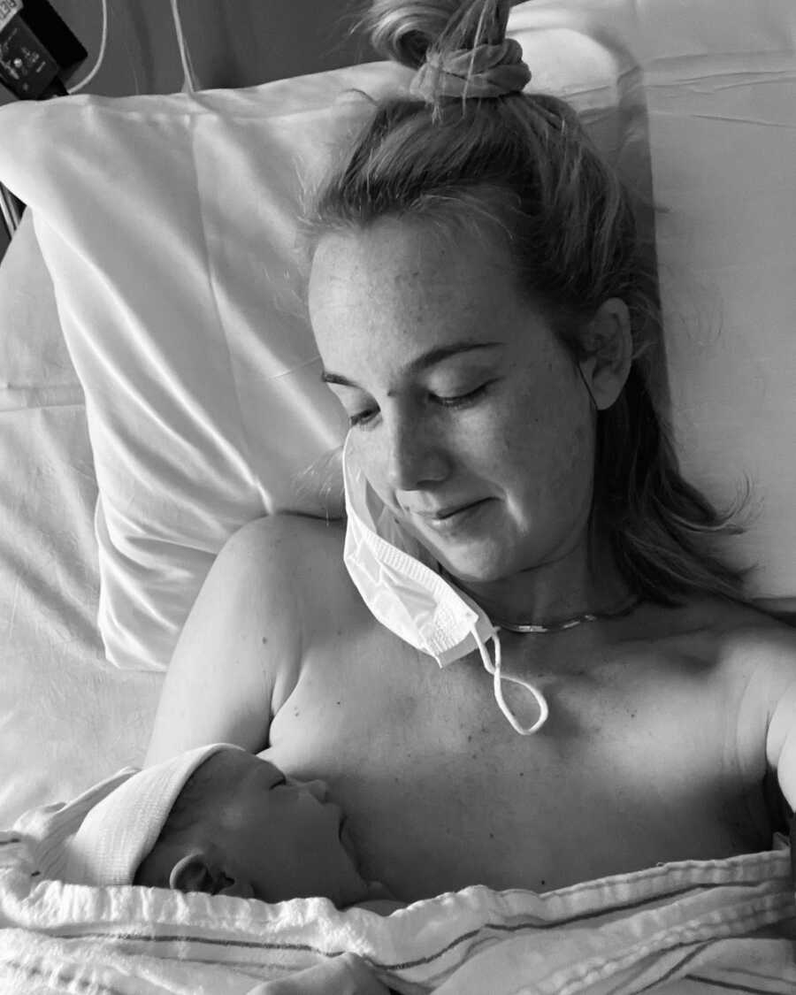 new mother sits in hospital bed with her newborn baby who is breast feeding