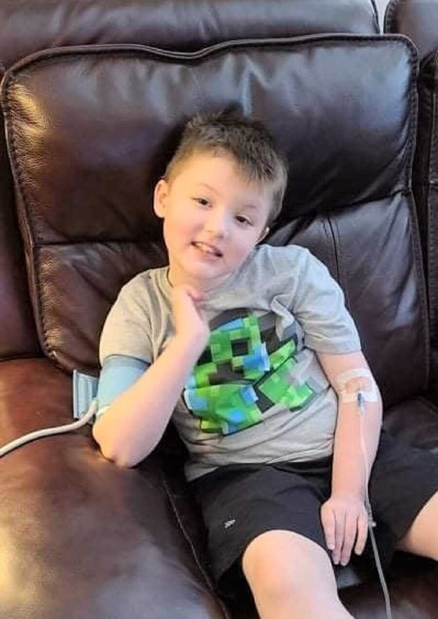 Young boy with Duchenne Muscular Dystrophy sits on the couch while IV pumps medication into his arm.