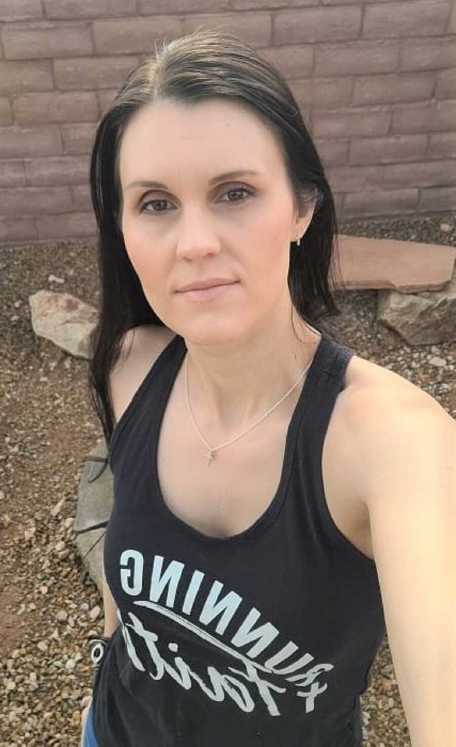 Duchenne mom takes picture wearing black "Running On Faith" tank top.