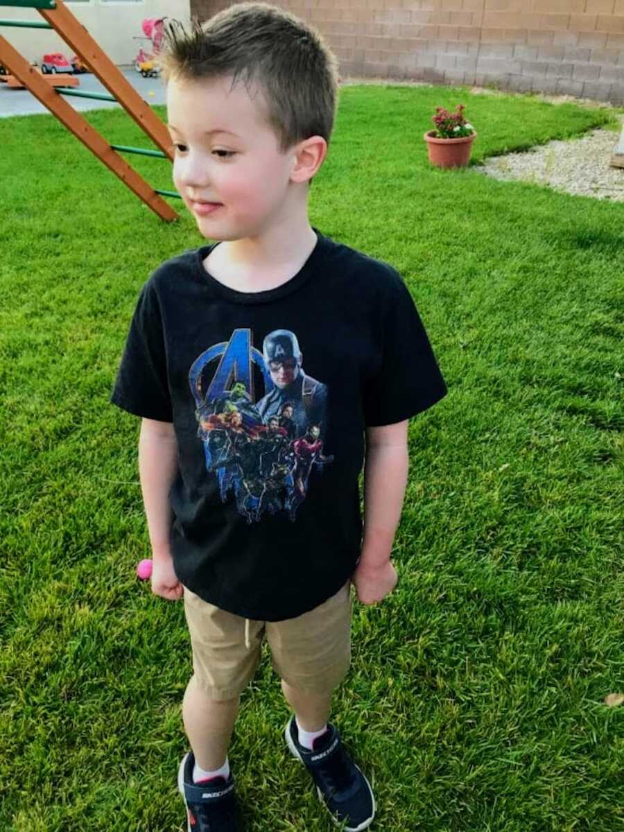 young boy with Duchenne's stands outside looking away from the camera