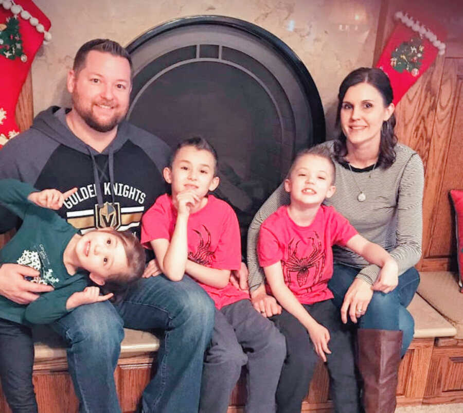 Family of five poses in front of a fireplace, two sons who have Duchenne's posed between their parents with their sister