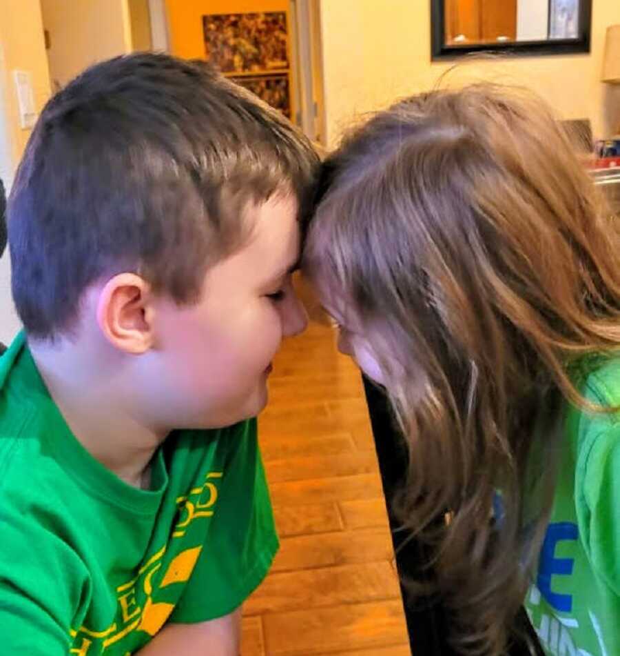 young boy with Duchenne's rests his forehead against his sisters, their faces are close to each other