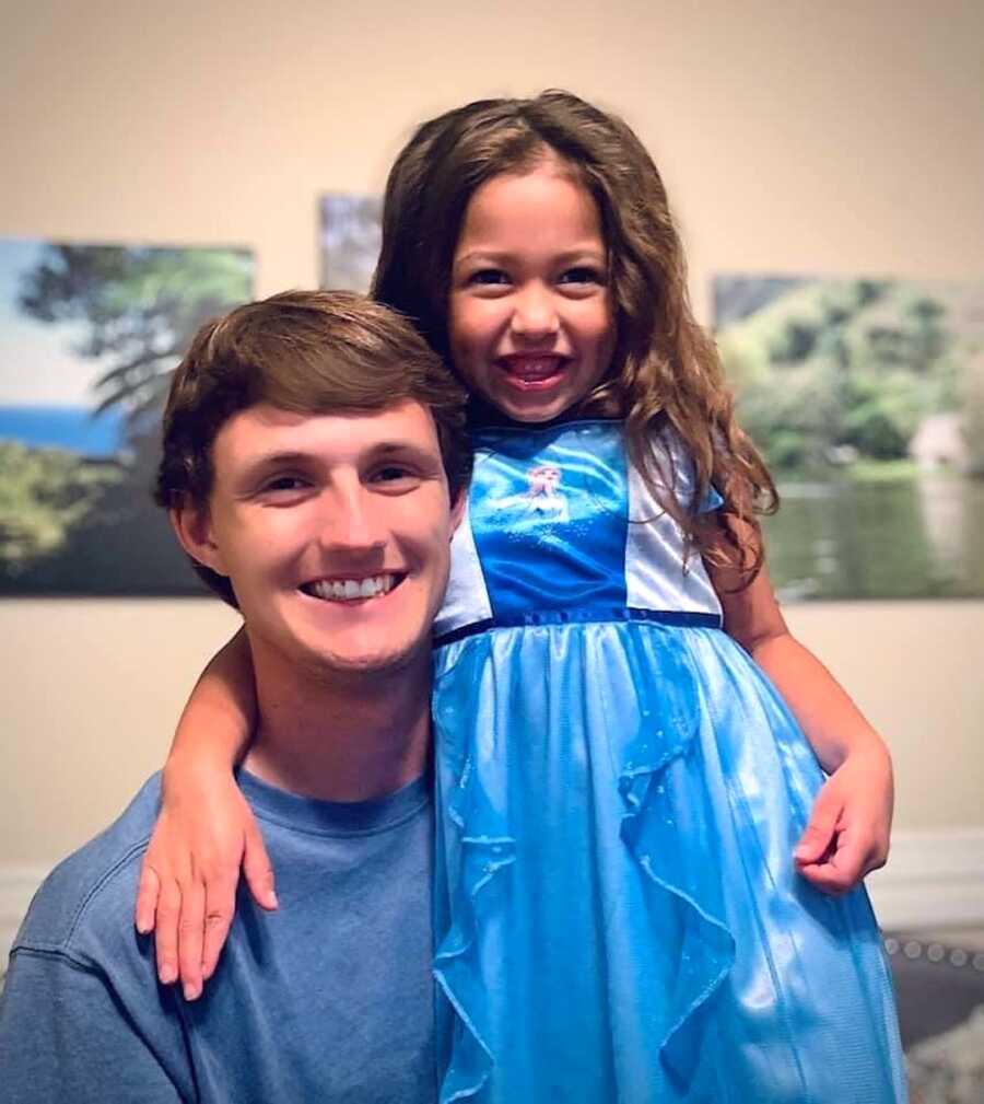 teenage son poses with his niece, she is wearing a princess dress, both of them are smiling