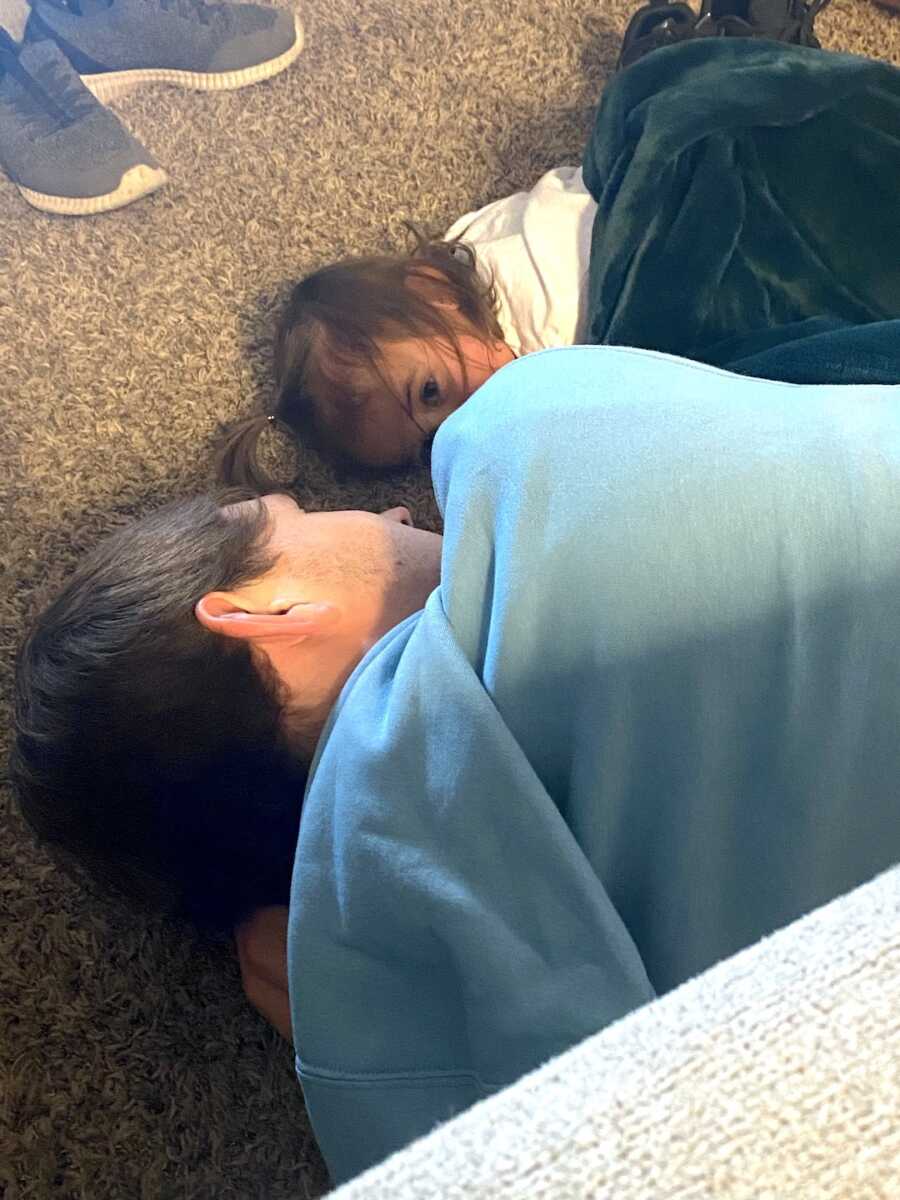teenage son lays on the floor facing his niece, they look at each-other lovingly