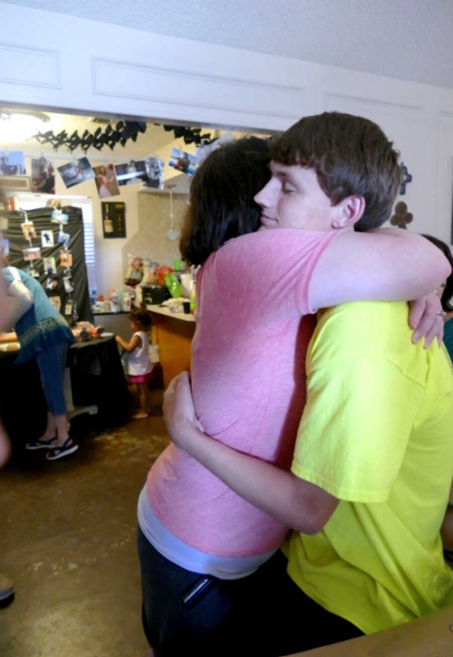 mom tightly hugs young adult son