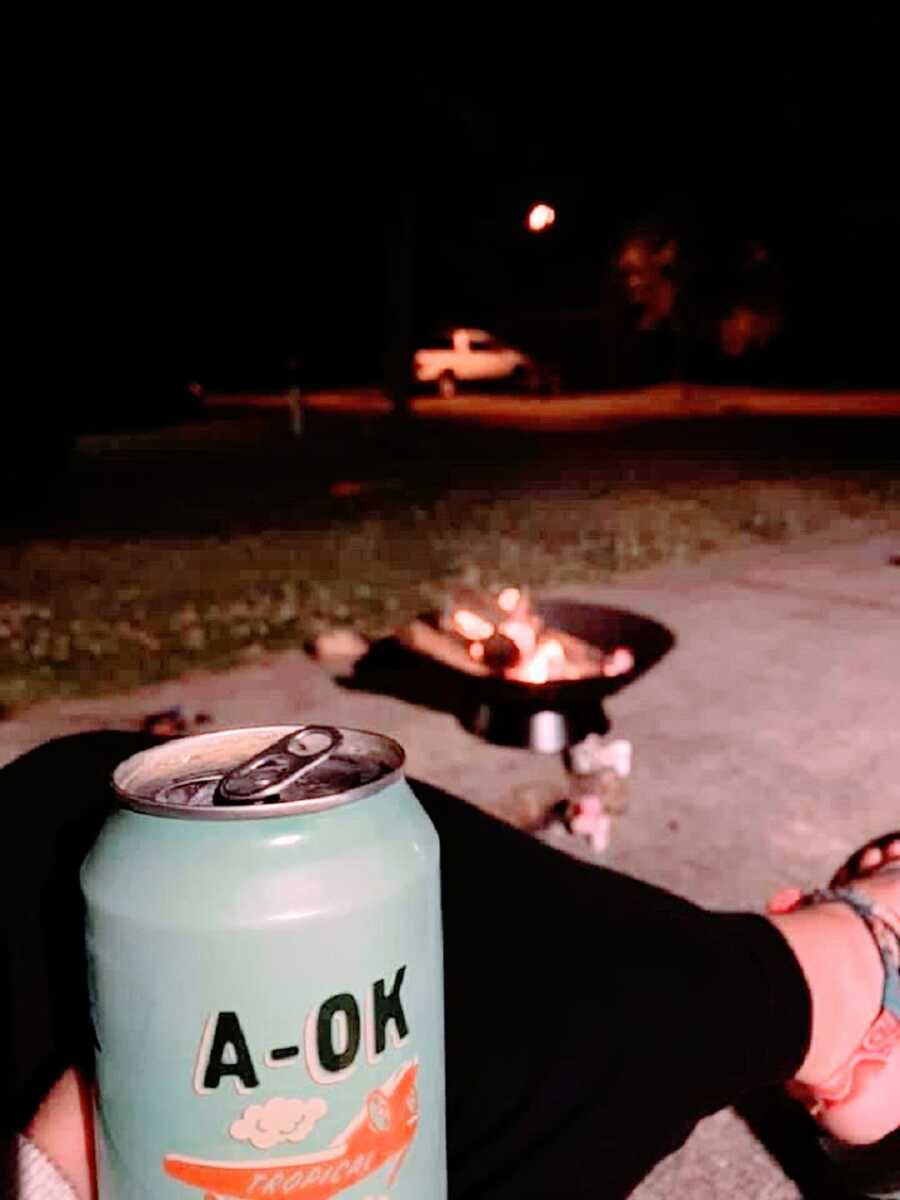 A mom holds an alcoholic beverage outside