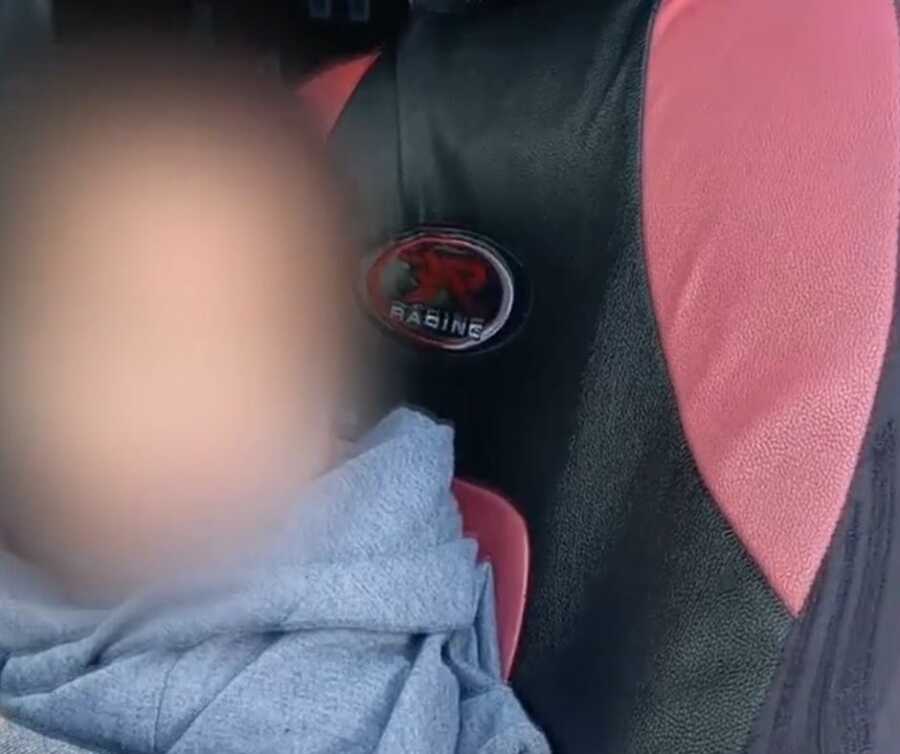 Young toddler rescued by DoorDash delivery driver sits in their car to warm up.