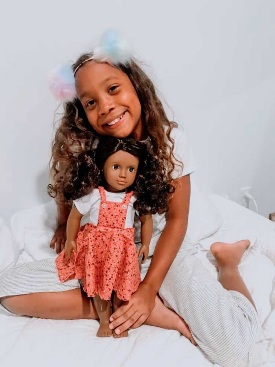 young African American girl holds doll that looks like her