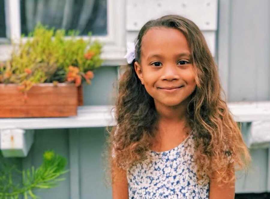 cute African American girl takes picture in front of house