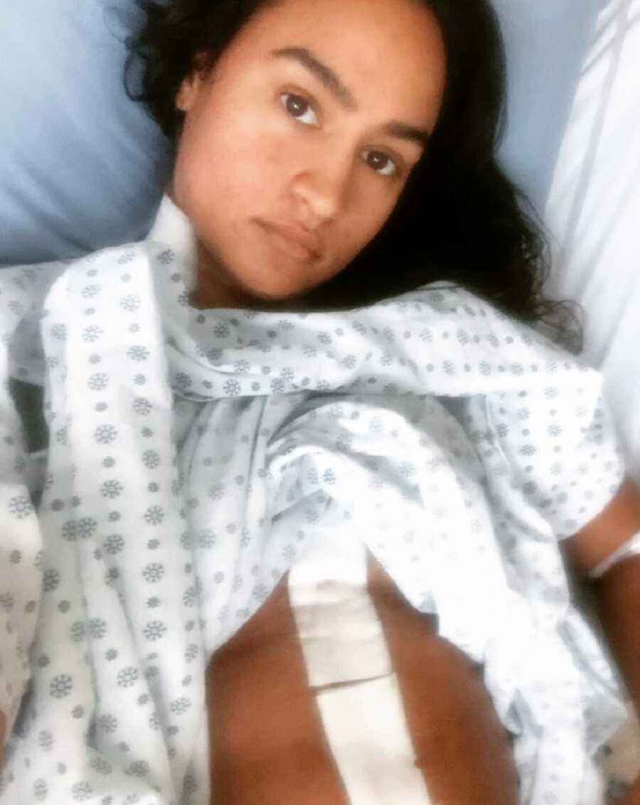 A woman lying in a hospital bed with a scar on her stomach