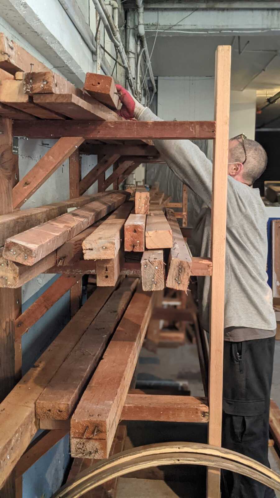 formerly incarcerated employee places wood planks on shelves above his head