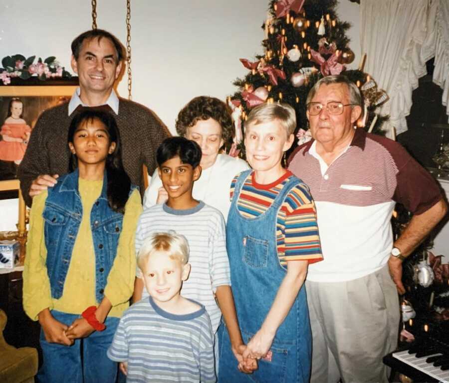 interracial, international family takes picture with grandparents while visiting for Christmas