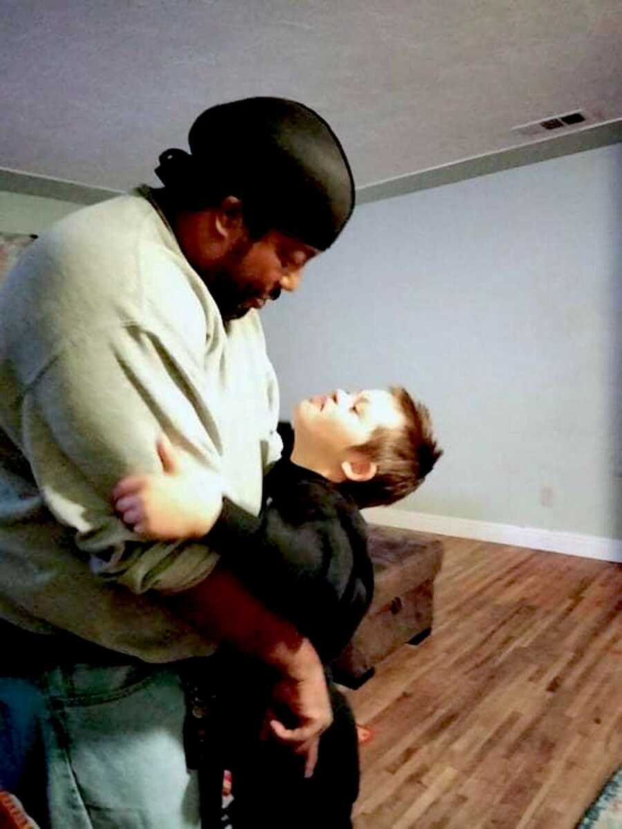 young boy with down syndrome hugs man and looks up at him