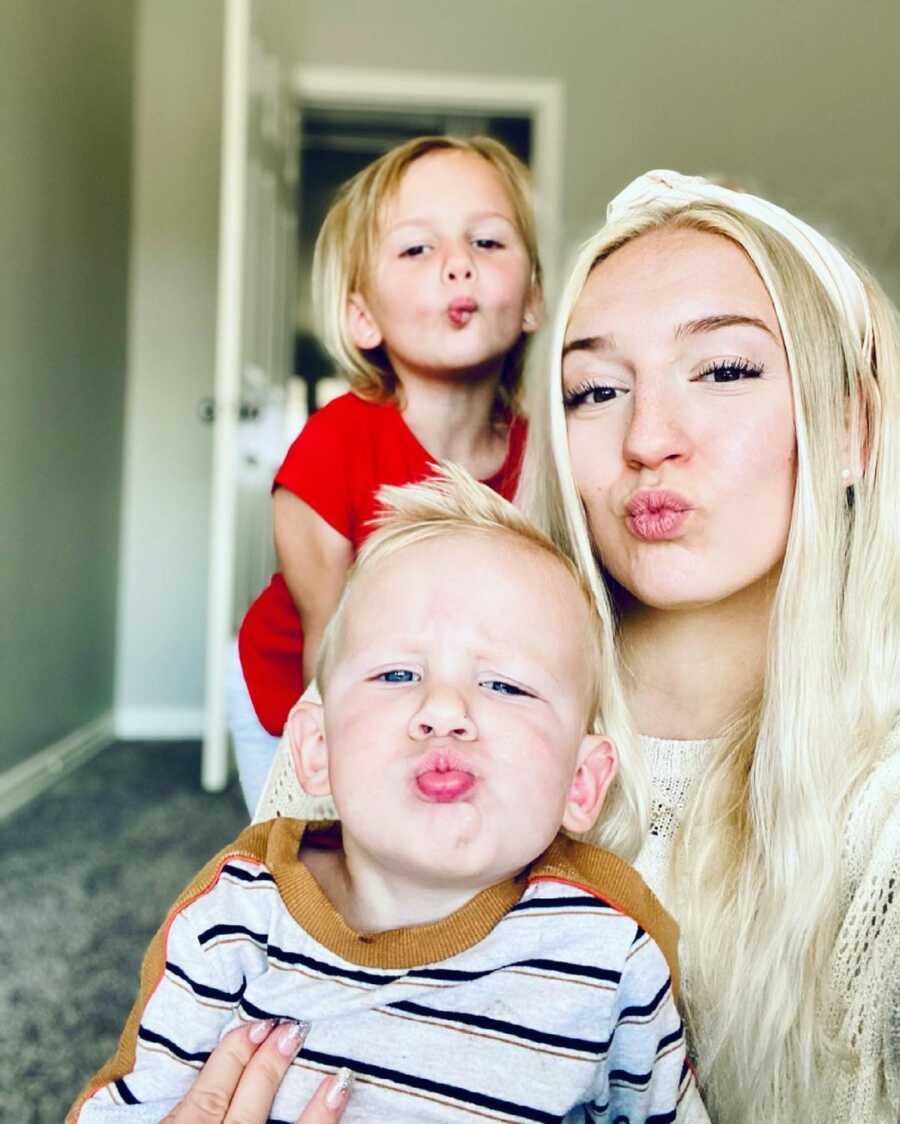 mother takes a selfie with her son and daughter, all three of them are making a kissy face