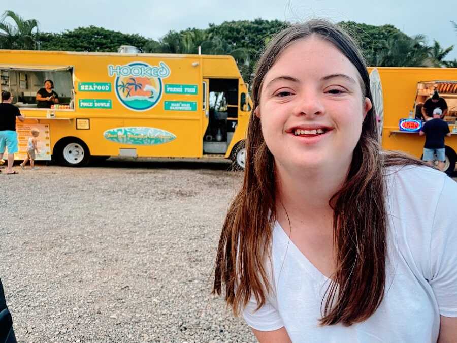 A girl with down syndrome in front of a food truck