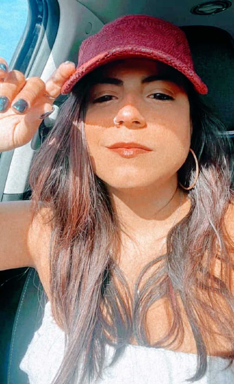 A suicide attempt survivor in a car wearing a hat