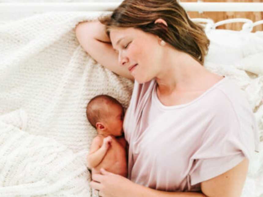mom laying on the bed breastfeeding her child