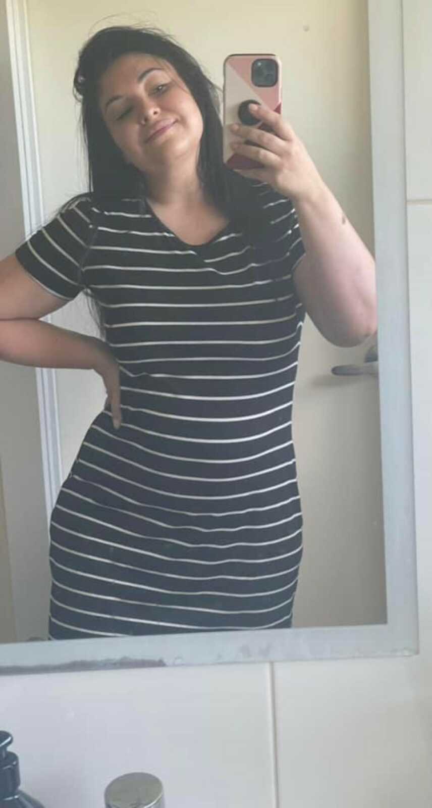 woman in a striped dress taking a selfie in the mirror
