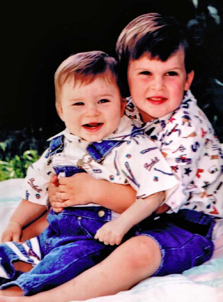 A boy holds his brother with a limb difference