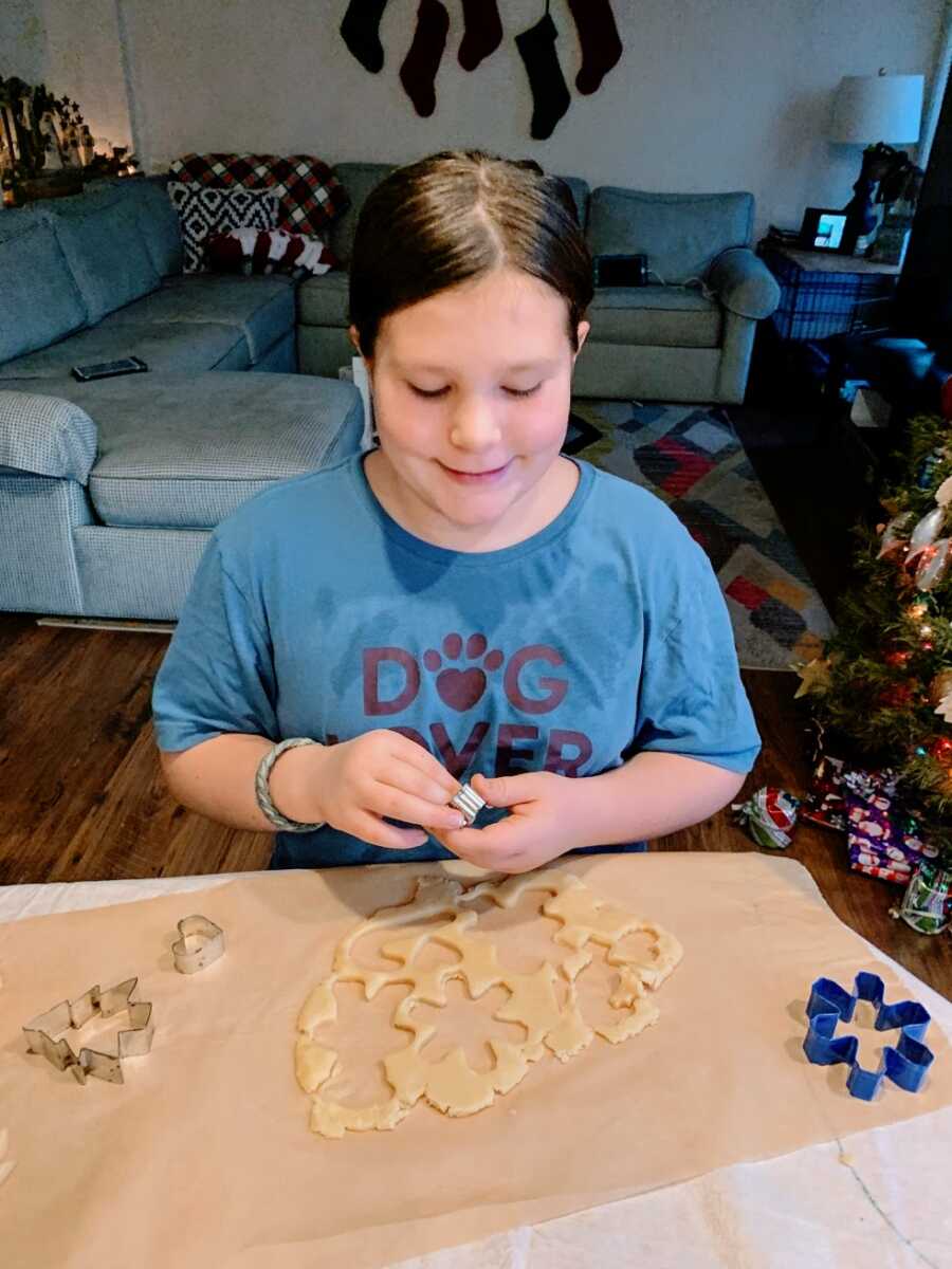 A little girl makes Christmas cookies with stencils