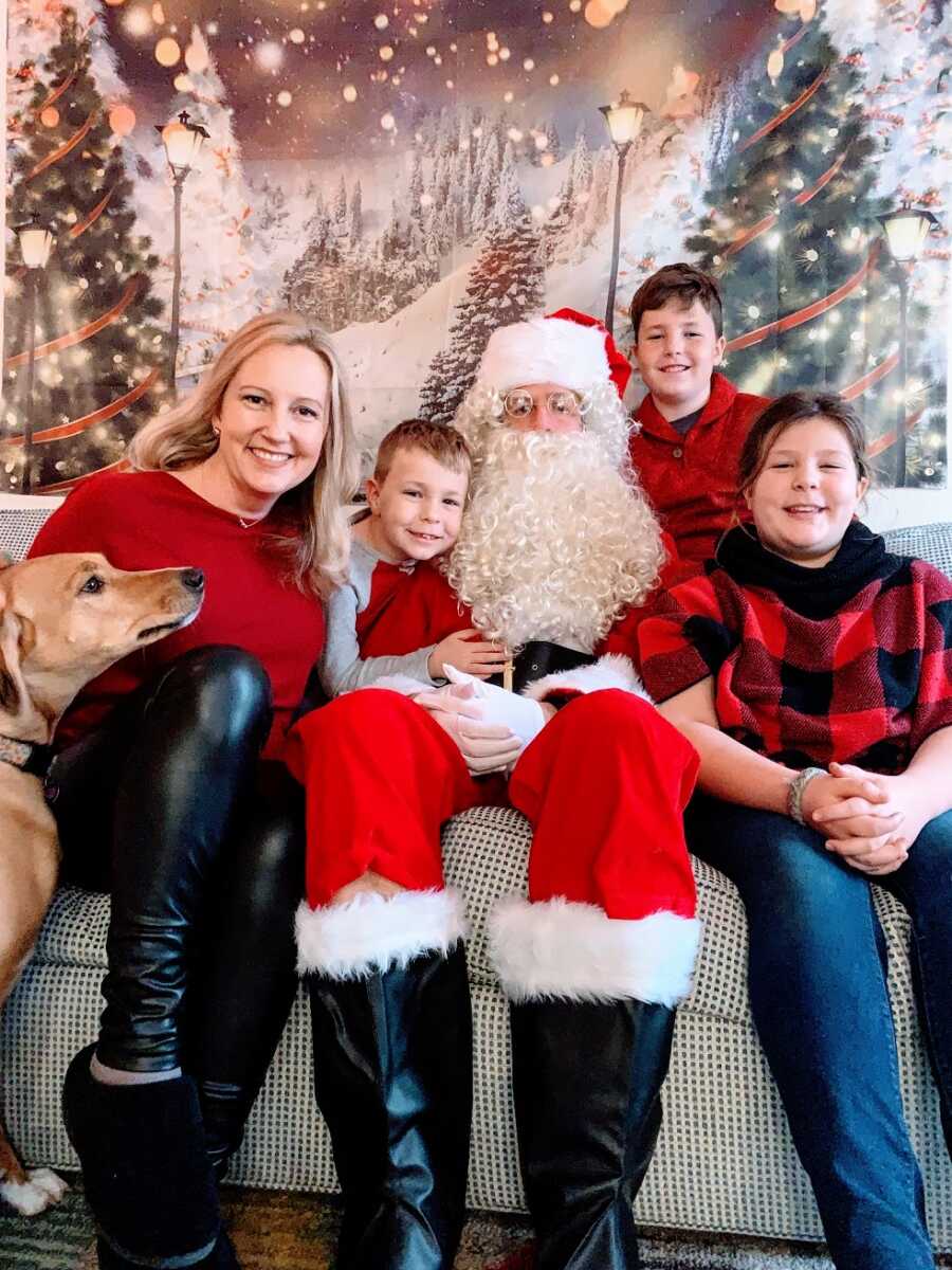 A family sitting on a couch with Santa Claus