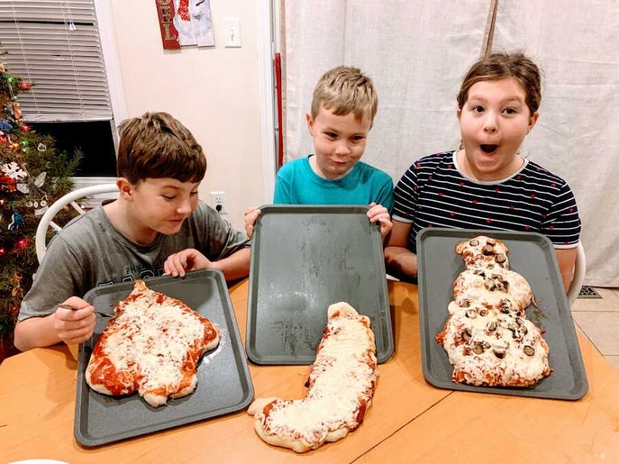 Children holding up homemade pizzas