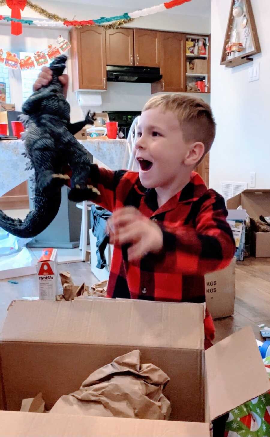 A young boy holds up a toy from a box