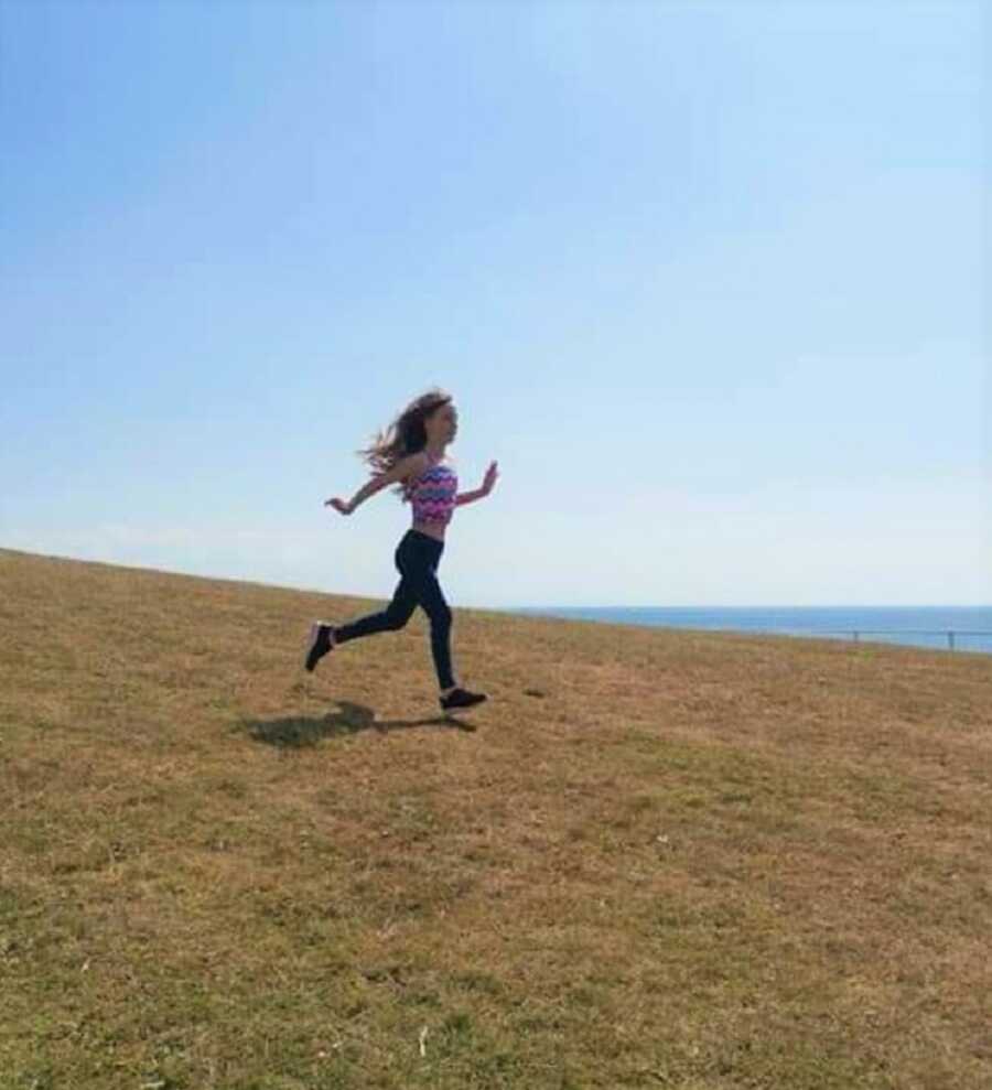 anxious teenage daughter runs down grassy hill